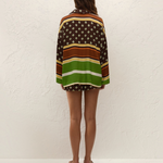 A person viewed from behind wearing a vacation-ready Cora Shirt and matching shorts in a geometric and striped pattern of brown, green, and white.