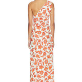 A woman with long dark hair, seen from behind, stands barefoot against a white background wearing the Chloe One Shoulder Midi Dress—a white linen midi dress with an orange floral print. Crafted in Turkey from lightweight, fully lined linen for comfort.