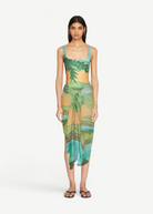 KABE SHOP INC Magdalena Pareo featuring a fluid landscape print in green and orange, worn as a wrap skirt.
