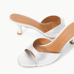 Brigitte Heel silver metallic kitten-heel mules with an open toe and tan leather footbed, featuring a refined silhouette.