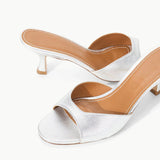 Brigitte Heel silver metallic kitten-heel mules with an open toe and tan leather footbed, featuring a refined silhouette.