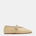 A pair of Stella Slipper Leather Shoes in custard leather, designed in a beige hue with a flat sole, pointed toe, and an elegant buckle. A single silver strap crosses the instep, displayed on a white background.