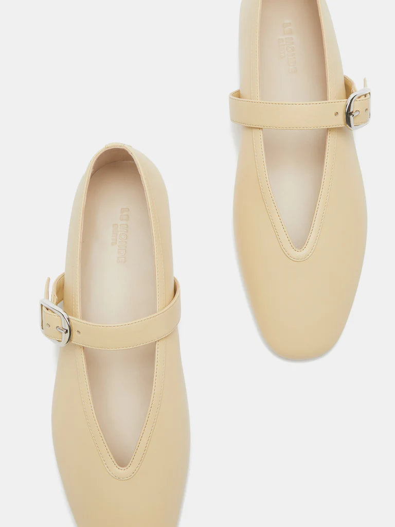 A pair of Stella Slipper Leather Shoes in beige custard leather, featuring a rounded toe, a single strap with an elegant buckle across each shoe, and minimal stitching detail, displayed against a white background.