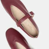 Top view of a pair of maroon Stella Slipper Leather Shoes crafted from rouge leather, featuring a polished buckle strap and beige insoles, displayed on a white background.