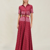 A model wearing a Rosie Top, a cropped, short-sleeved button-down shirt, paired with a matching high-waisted maxi skirt in a deep red bandana print.