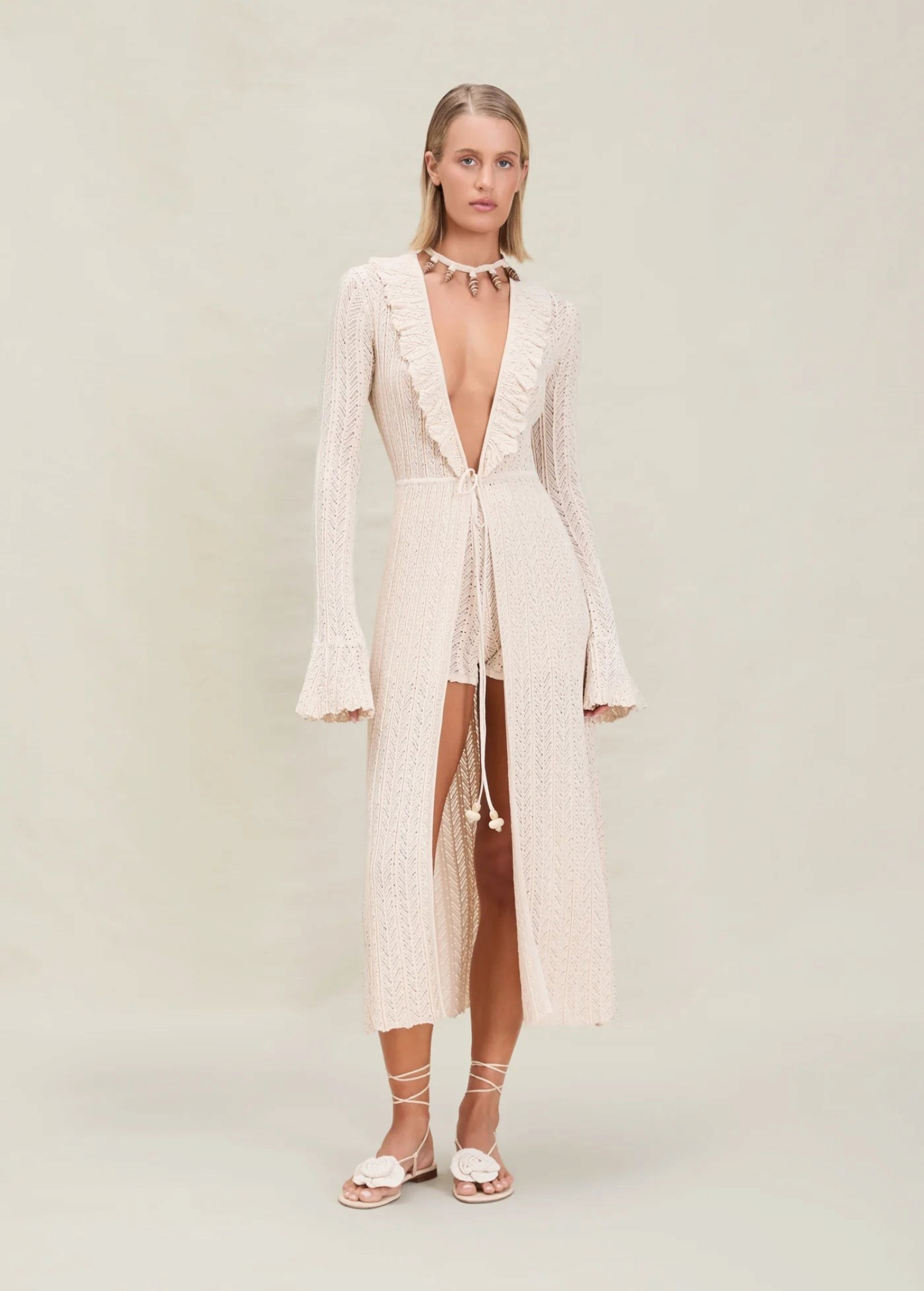 Model wearing KABE SHOP INC Sienna maxi knit robe in cream with ruffle neckline and beaded front tie closure