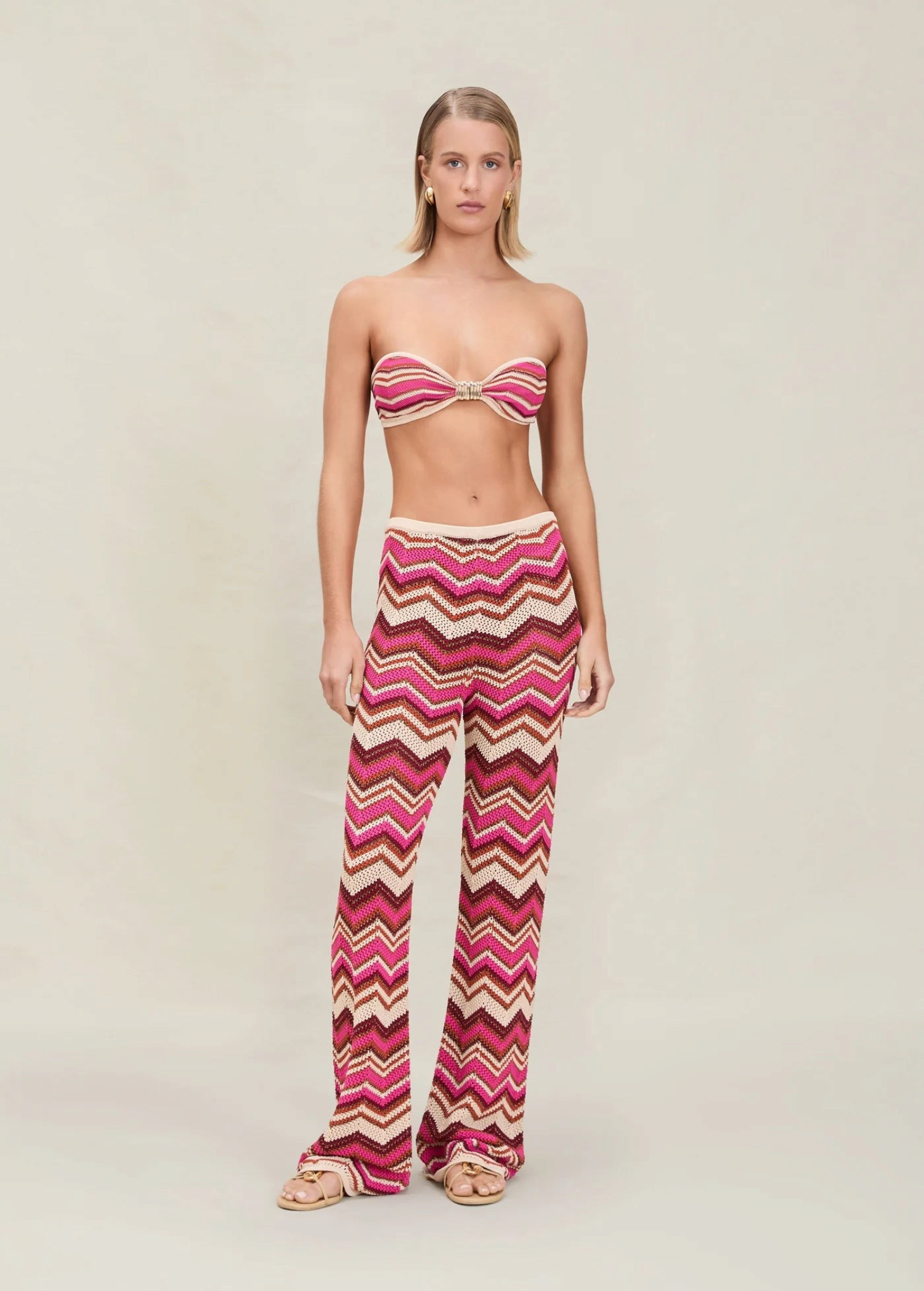 Model wearing KABE SHOP INC Cierra knit pants featuring a pink, brown, and cream chevron pattern with elastic waist.