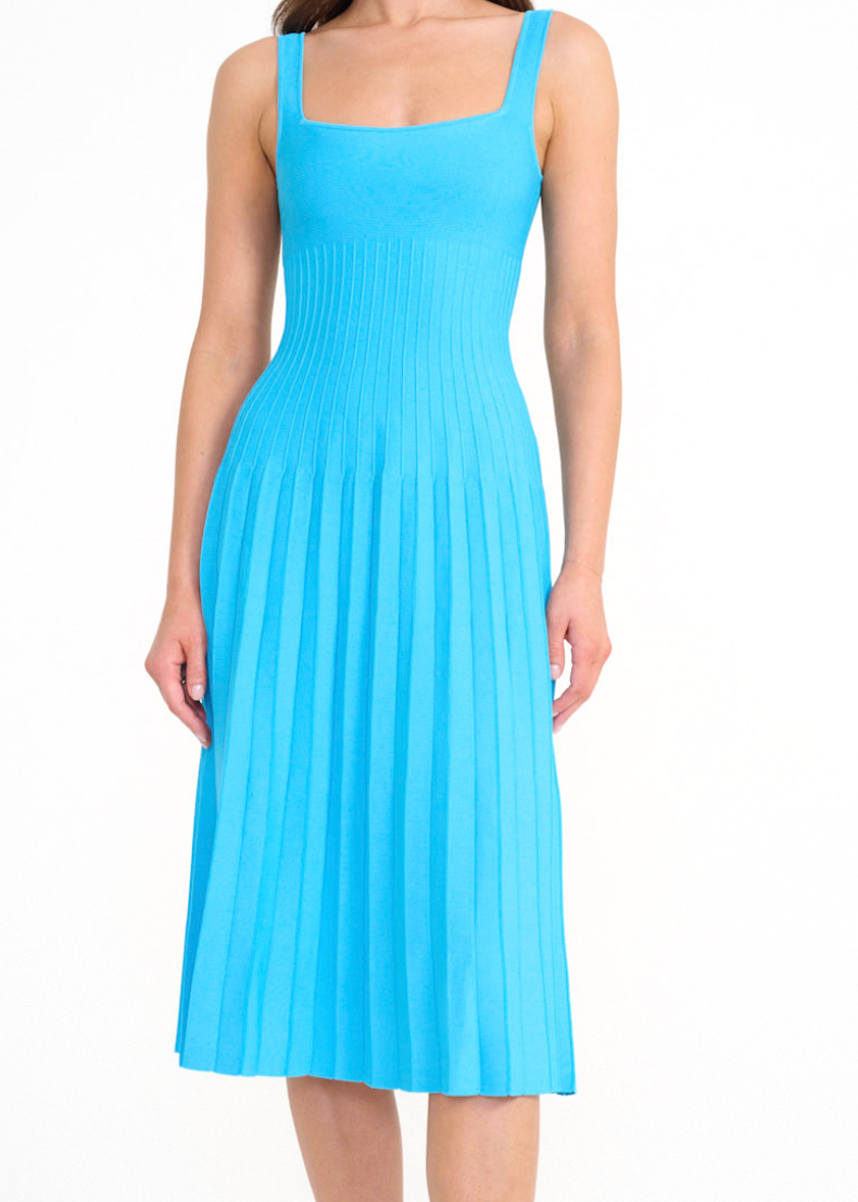 A woman wears a cobalt Ellison Dress, a sleeveless midi with a square neckline and a pleated skirt for a flattering fit.