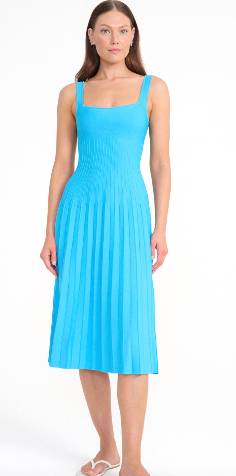 A woman wears a cobalt Ellison Dress, a sleeveless midi with a square neckline and a pleated skirt for a flattering fit.