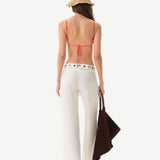Woman wearing a white outfit with colorful accents and a straw hat on a white background
