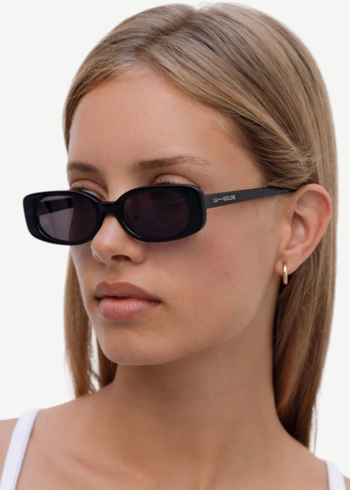 A woman with straight, light brown hair wears the Solene black slim rectangle sunglasses, which offer 100% UV protection, along with a small gold hoop earring. She is looking to the side with a neutral expression, dressed in a white top against a plain background.