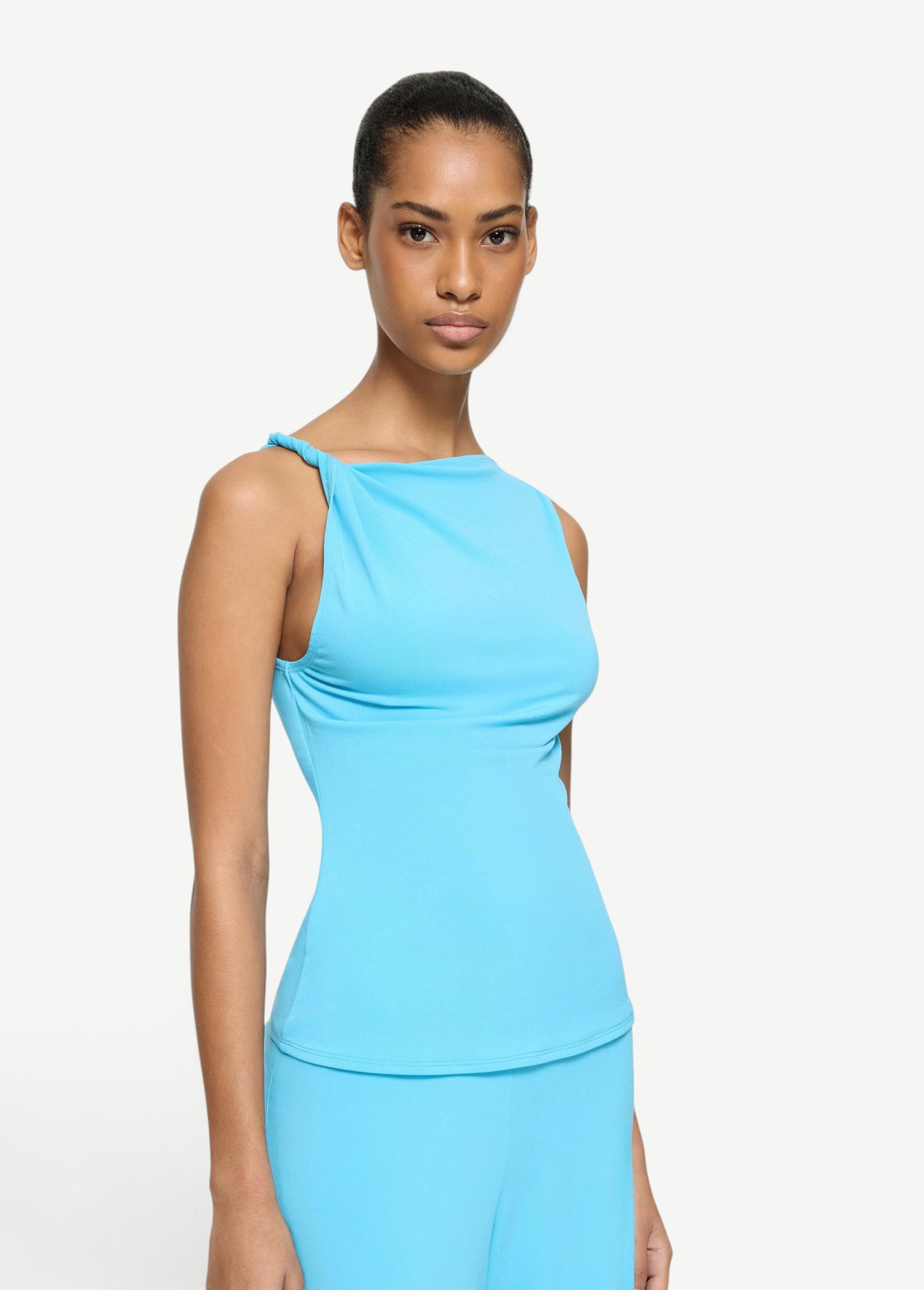 Elemental Twist Singlet in bright blue, featuring a sleeveless design with a sculptural shoulder and twisted strap detail.