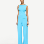 A person wears a bright blue Elemental Twist Singlet with an asymmetrical drape at the shoulder, paired with matching wide-leg pants.