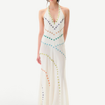 A person stands against a plain white background wearing the Vicka Dress—a sleeveless, floor-length white backless dress embellished with colorful circular beads arranged in curved lines, featuring intricate bead embroidery and a subtly flared hemline.