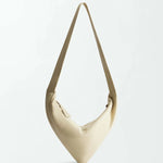 The Vancouver Sling Bag, shown against a plain white background, is a beige, triangular-shaped sculptural shoulder bag crafted from supple nappa leather and features a single strap.
