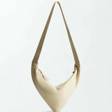 The Vancouver Sling Bag, shown against a plain white background, is a beige, triangular-shaped sculptural shoulder bag crafted from supple nappa leather and features a single strap.