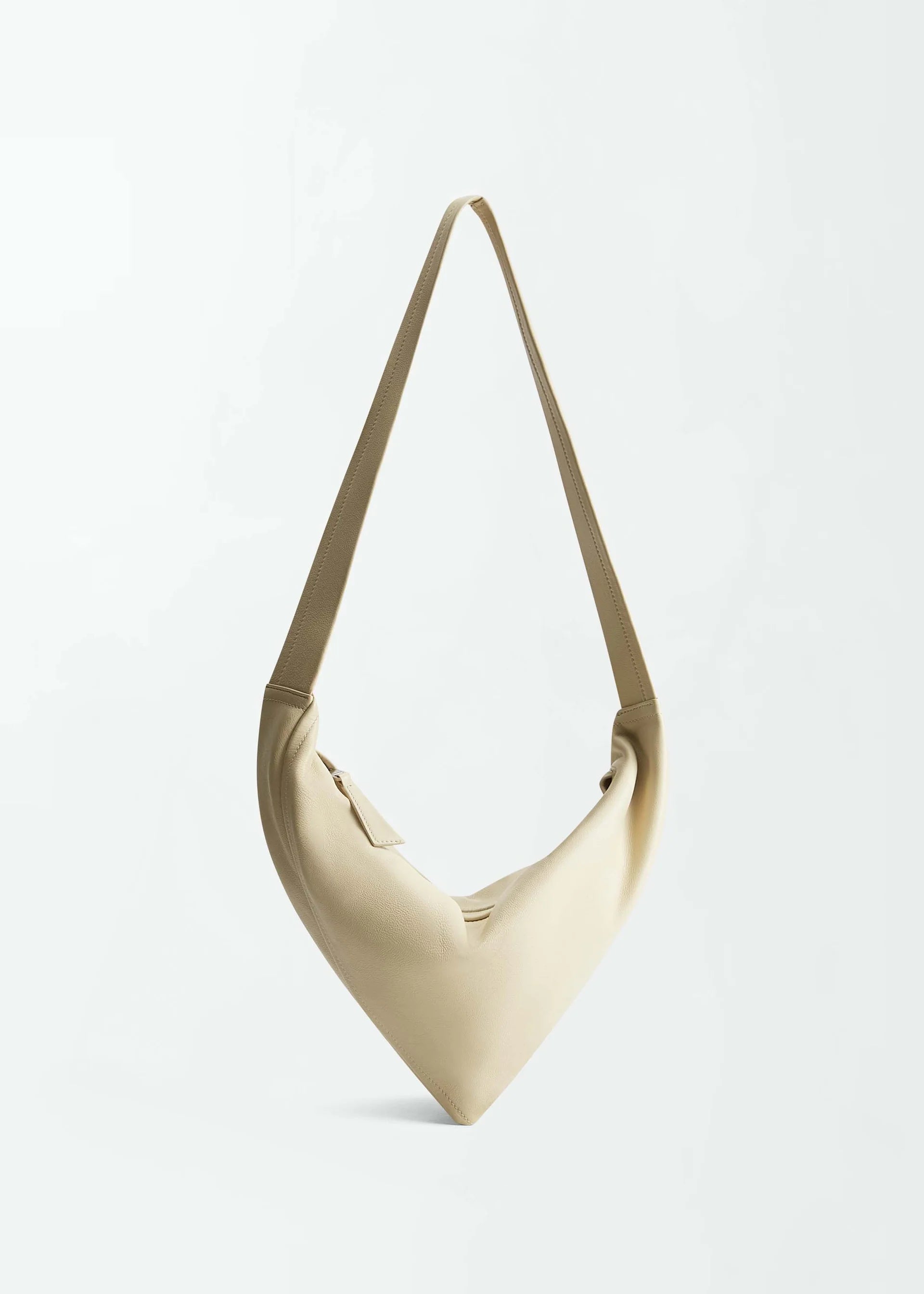 The Vancouver Sling Bag, shown against a plain white background, is a beige, triangular-shaped sculptural shoulder bag crafted from supple nappa leather and features a single strap.