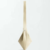 The Vancouver Sling Bag, crafted from supple nappa leather in beige, is displayed against a plain white background. Its geometric sculptural shape features clean lines, a minimalist design, and a single wide strap.