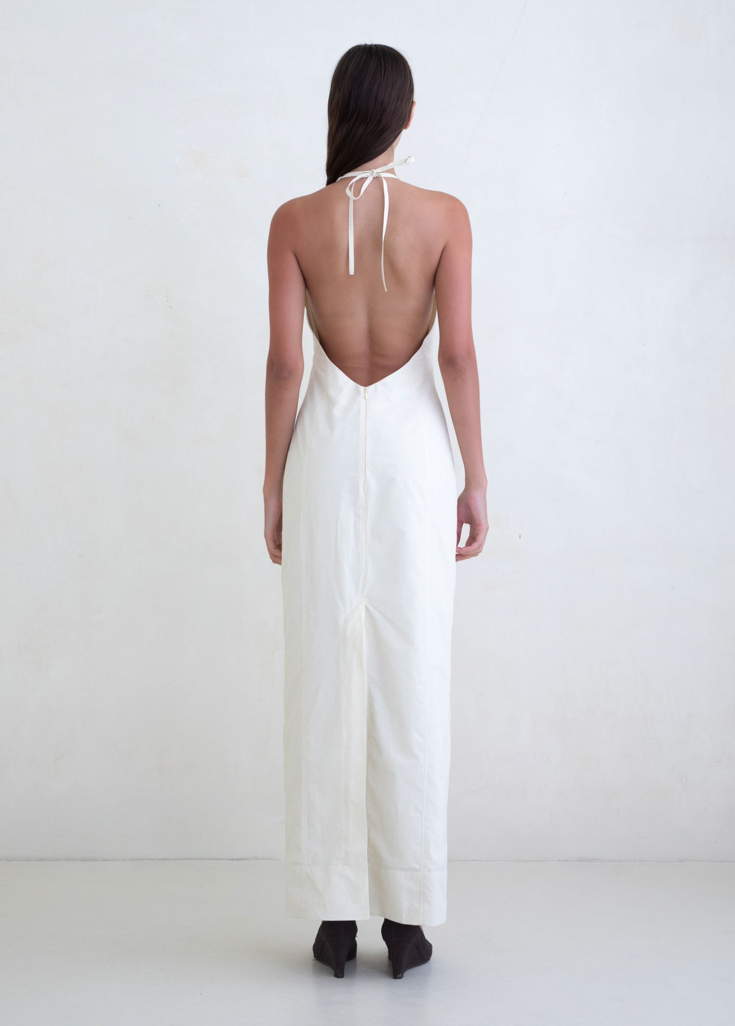 KABE SHOP INC Helia white halter gown with a plunging open back and floor-length silhouette on a model