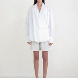 Model wearing KABE SHOP INC Leandra white convertible wrap shirt with long sleeves and relaxed fit