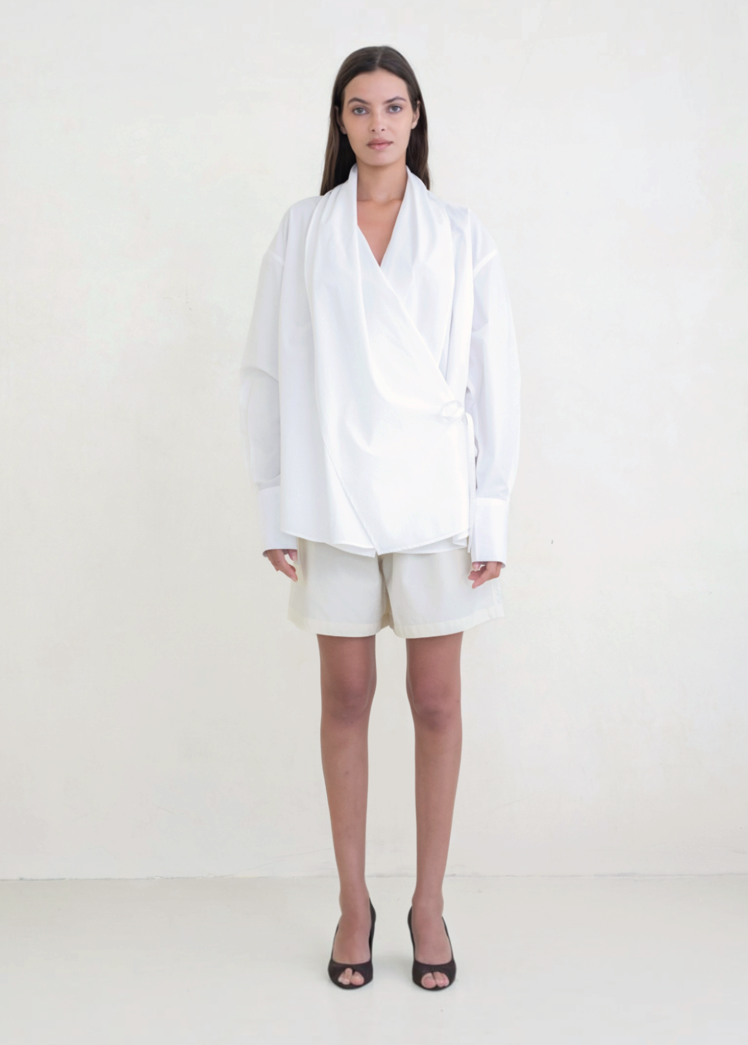 Model wearing KABE SHOP INC Leandra white convertible wrap shirt with long sleeves and relaxed fit