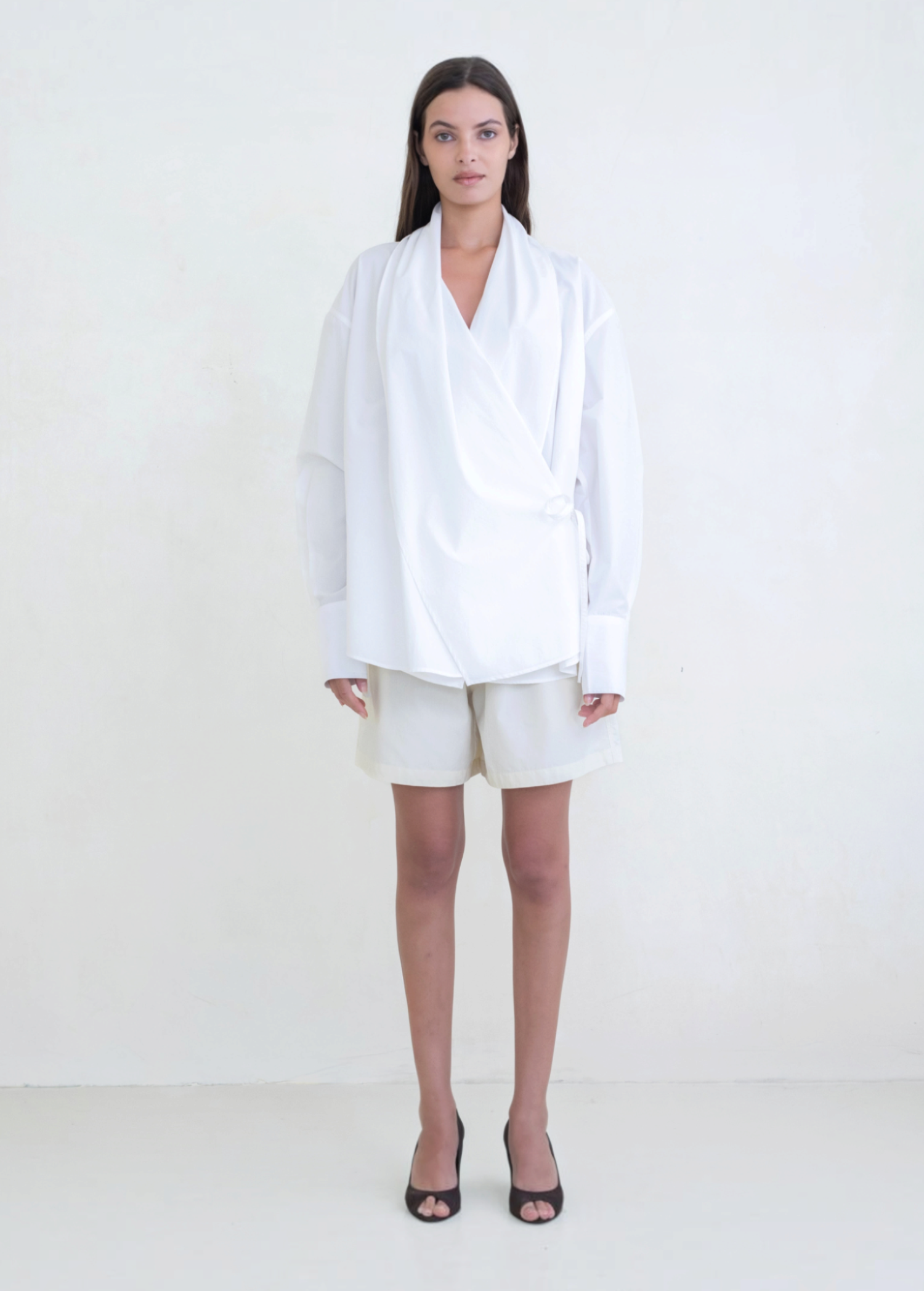 Model wearing KABE SHOP INC Leandra white convertible wrap shirt with long sleeves and relaxed fit