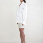 Model wearing a white KABE SHOP INC Leandra wrap shirt with long sleeves and a relaxed silhouette, side view.