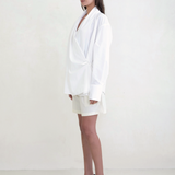 Model wearing a white KABE SHOP INC Leandra wrap shirt with long sleeves and a relaxed silhouette, side view.