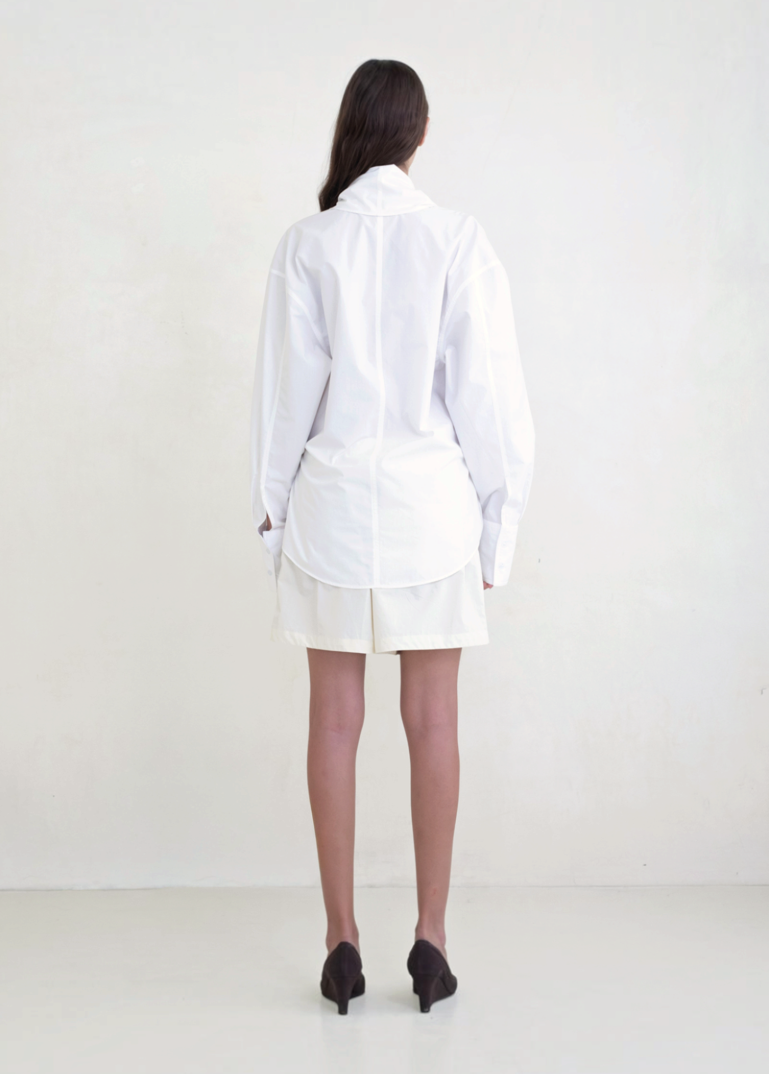 Back view of a model wearing the white KABE SHOP INC Leandra wrap shirt with a relaxed fit and long sleeves.