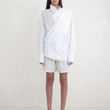 Model wearing KABE SHOP INC Leandra white convertible wrap shirt with long sleeves and relaxed fluid silhouette
