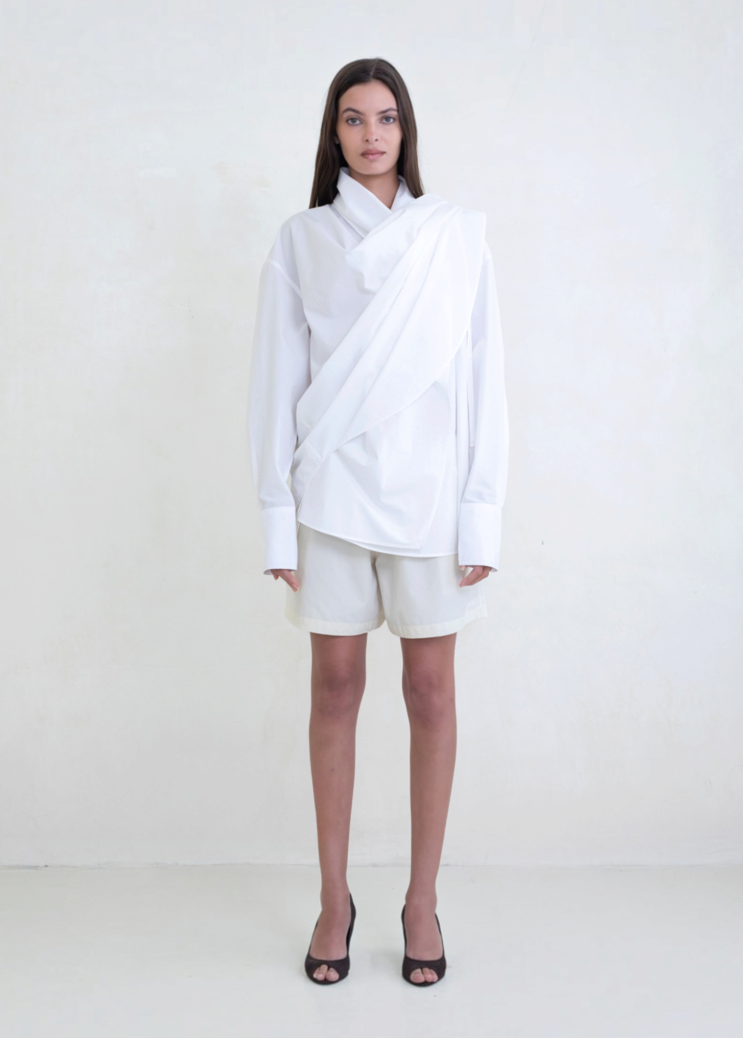 Model wearing KABE SHOP INC Leandra white convertible wrap shirt with long sleeves and relaxed fluid silhouette