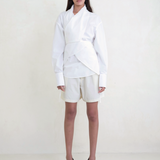 Model wearing KABE SHOP INC Leandra white convertible wrap shirt with long sleeves and tailored shorts