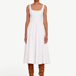 Model wearing a white KABE SHOP INC Wells midi dress with a square neckline and pleated skirt, paired with brown boots.