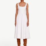 Model wearing a white KABE SHOP INC Wells midi dress with a square neckline and pleated skirt, paired with brown boots.