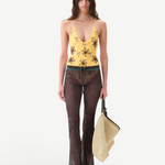 Model wearing KABE SHOP INC Flo pants in sheer brown with lace-up waist and lettuce-edge hem, paired with yellow top.