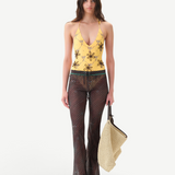 Model wearing KABE SHOP INC Flo pants in sheer brown with lace-up waist and lettuce-edge hem, paired with yellow top.