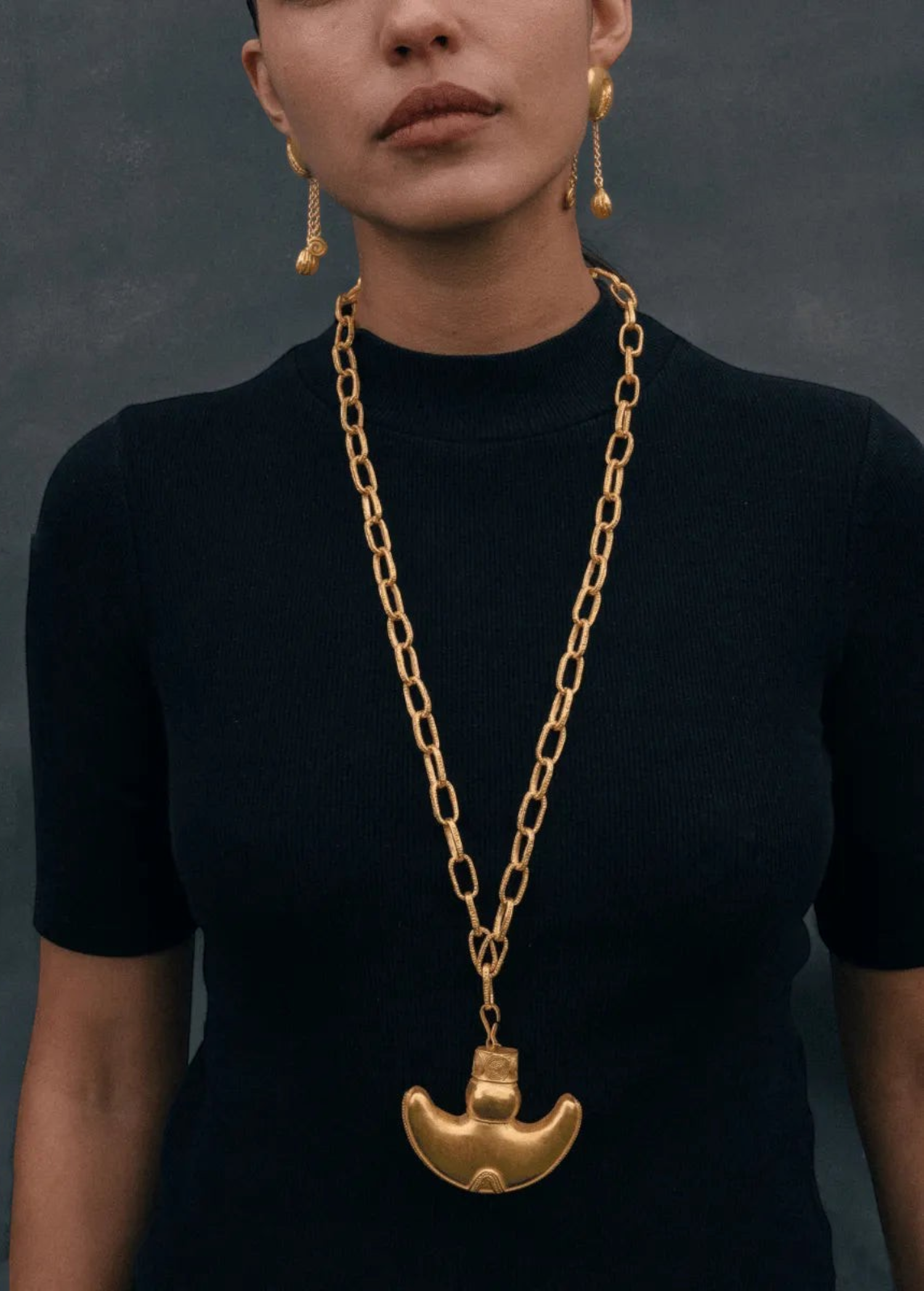 KABE SHOP INC Wanpu necklace featuring a gold anthropomorphic pendant on a chunky chain worn by a model