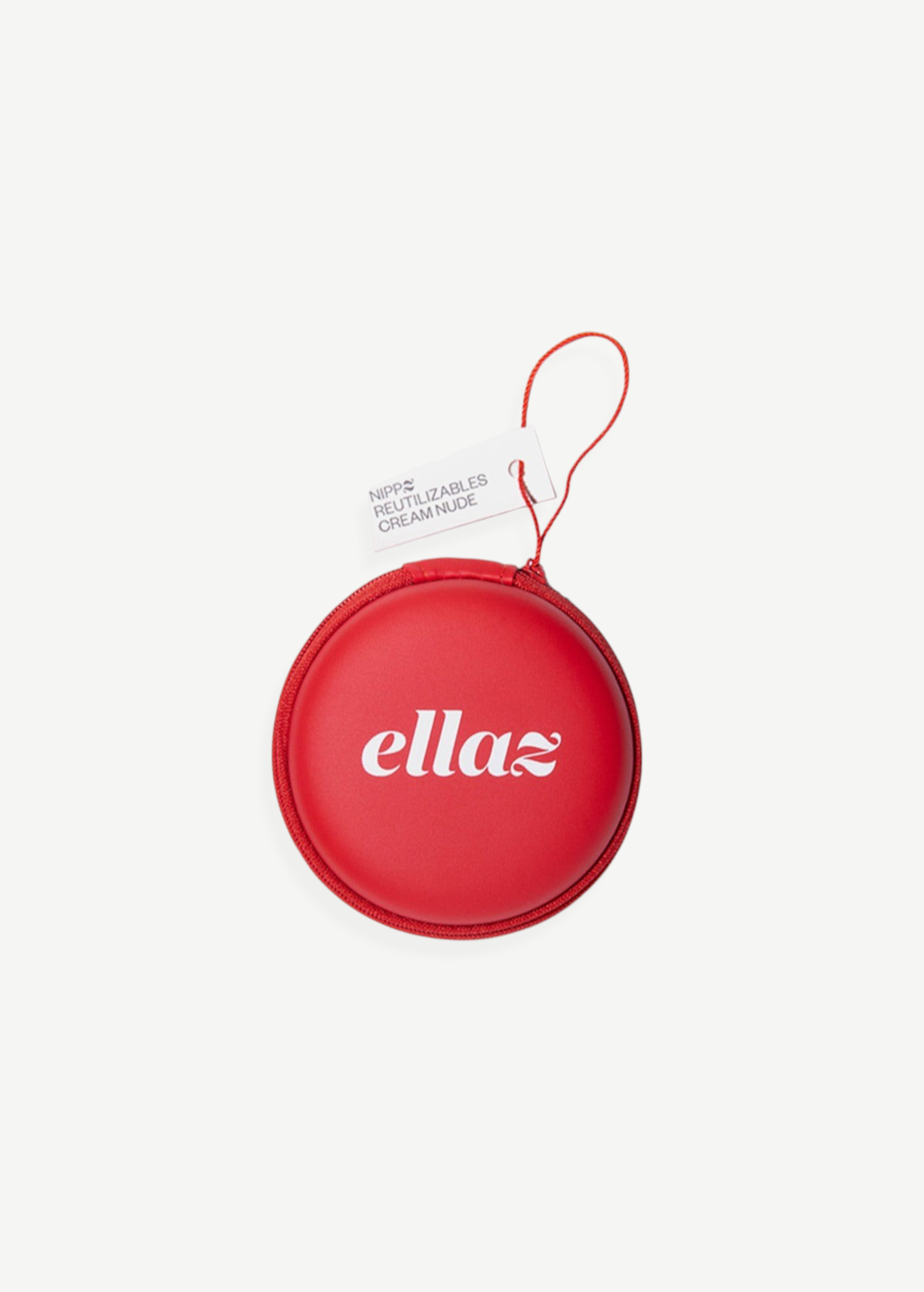 A round, red zippered case with “ellaz” printed in white letters houses Reusable Nippz nipple covers. A small attached tag reads “NIPPS, REUTILIZABLES, CREMA NUDE.” The case features a red wrist strap and is displayed against a plain white background.
