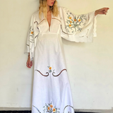 KABE SHOP INC white hand-knitted maxi dress with wide sleeves, floral embroidery, and cut-out details on a model.