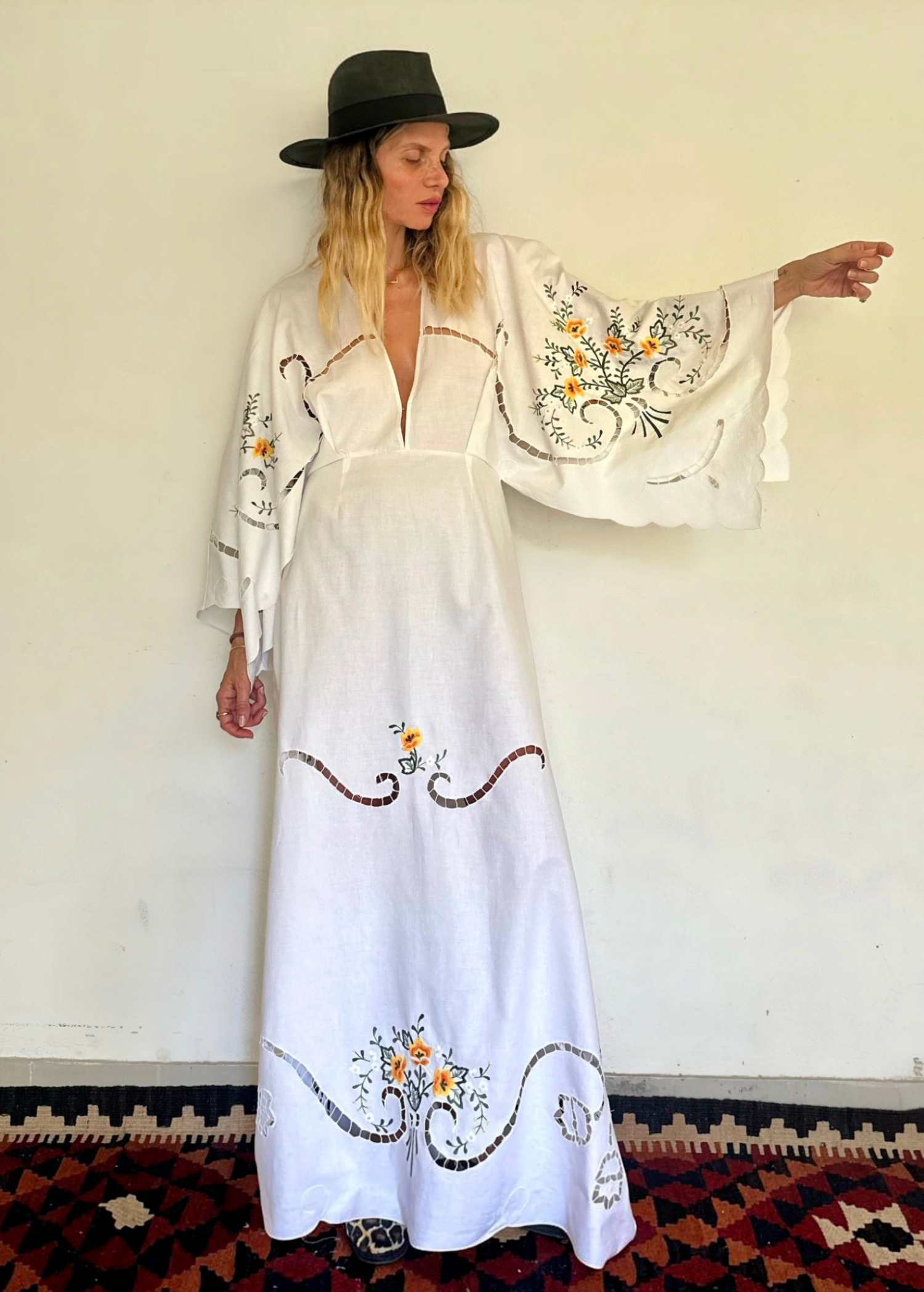 KABE SHOP INC white hand-knitted maxi dress with wide sleeves, floral embroidery, and cut-out details on a model.