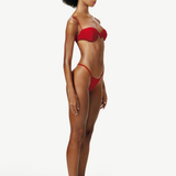 Model wearing a KABE SHOP INC red balconette bikini top with delicate straps and underwire, side profile view.