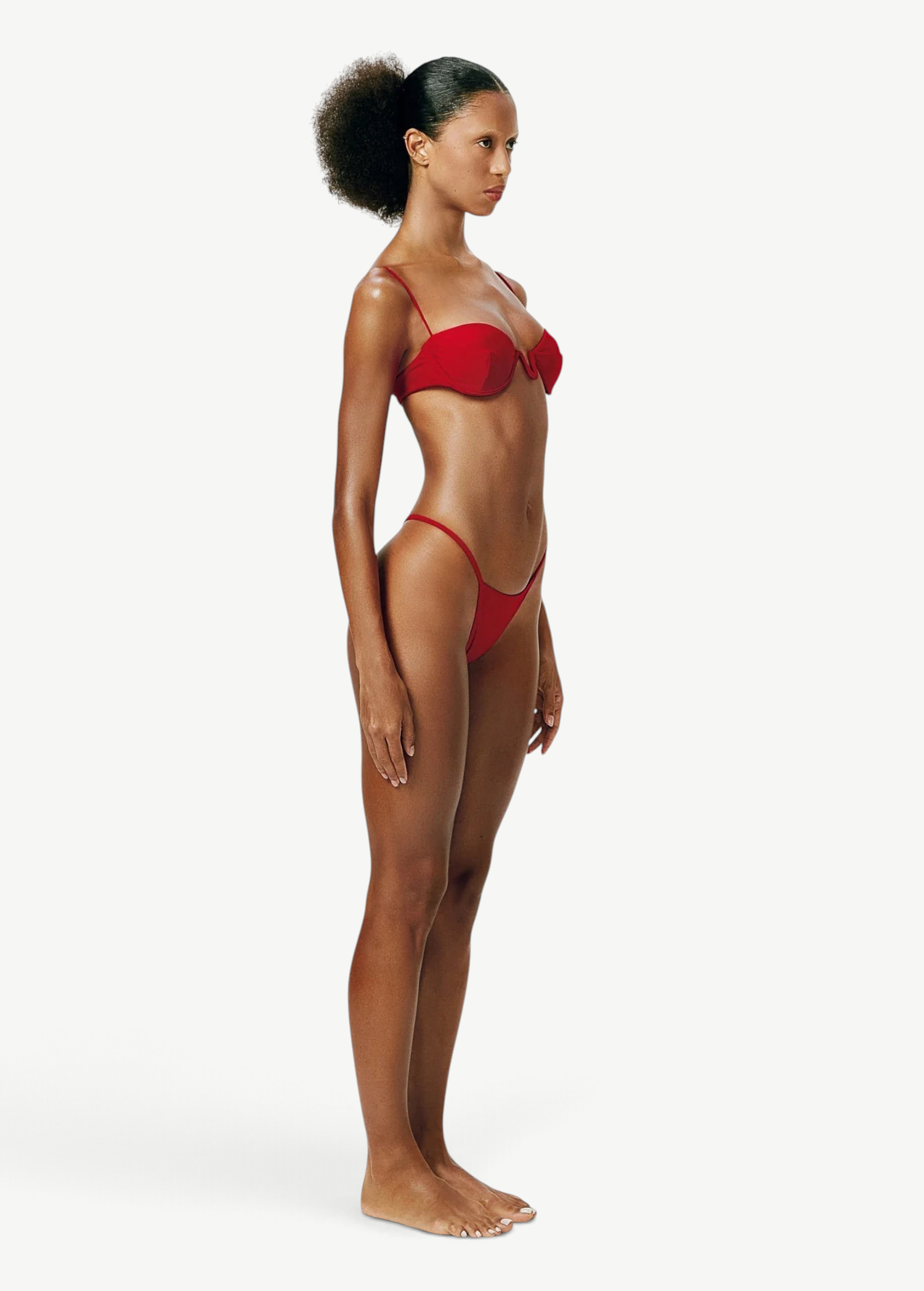 Model wearing a KABE SHOP INC red balconette bikini top with delicate straps and underwire, side profile view.