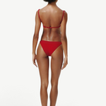 Model wearing KABE SHOP INC Classic Bottom in red, featuring a flattering medium-stretch recycled fabric design.