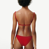 Model wearing KABE SHOP INC Classic Bottom in red, featuring a flattering medium-stretch recycled fabric fit.