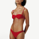 Model wearing KABE SHOP INC Classic Bottom in red, a recycled material bikini bottom with a flattering fit.