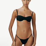 Model wearing KABE SHOP INC Copa Bottom, a black micro-cut bikini bottom with high-cut legs and slim side straps.