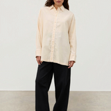 A person wears a pale yellow Shea Embroidered Hemp Blend Shirt with geometric floral embroidery along the placket, paired with wide-leg black trousers and black sandals.