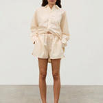 Model wearing KABE SHOP INC Shea hemp blend shorts in cream with white piping and elastic waistband