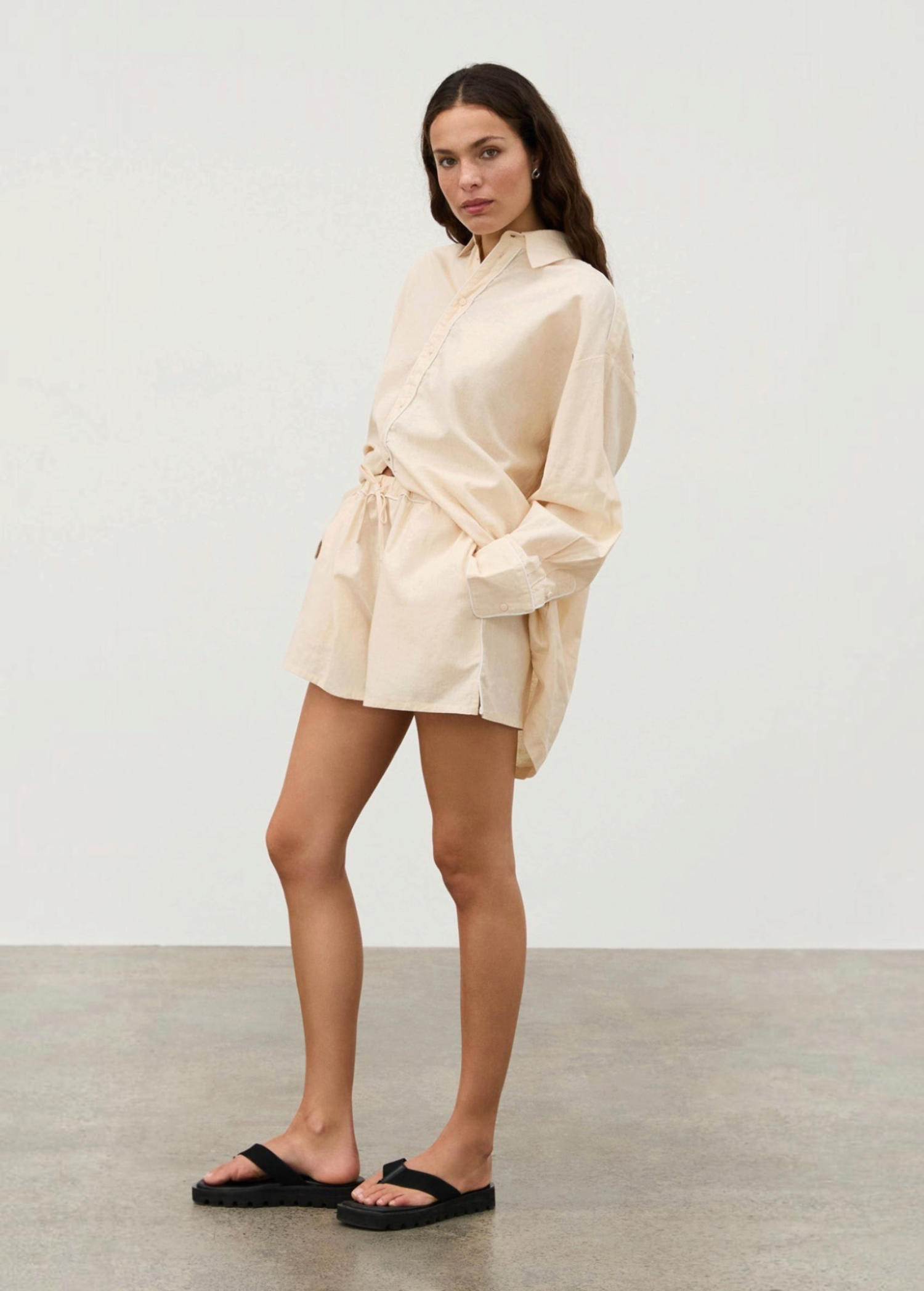 A person wearing a Shea Embroidered Hemp Blend Shirt in a light-colored hemp blend with geometric floral embroidery, matching drawstring shorts, and black platform sandals.
