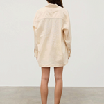 Back view of a person wearing a beige Shea Embroidered Hemp Blend Shirt with geometric floral embroidery on the back.